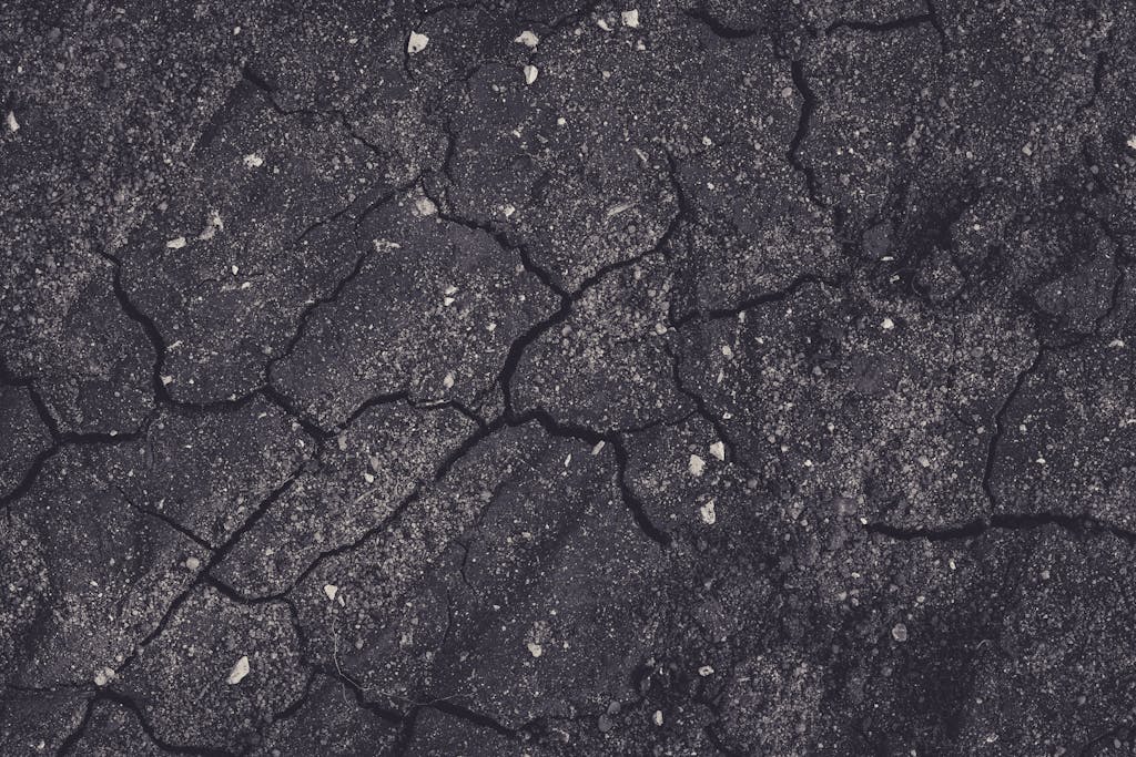 Close-up of cracked earth with dark tones, showcasing natural textures and patterns.
