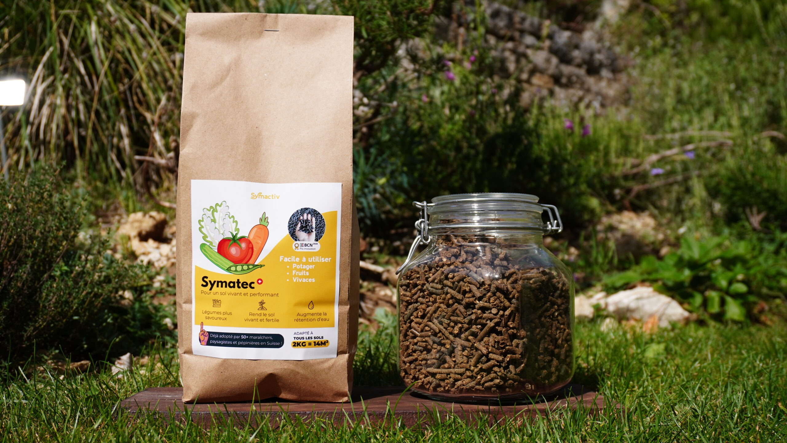 Sac Symatec+ et bocal de pellets sur une table en bois au jardin